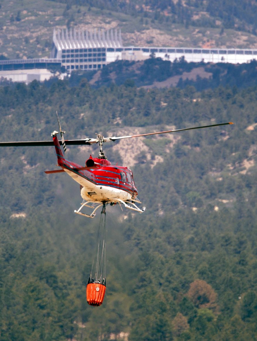 FILE - In this June 27, 2012, file photo, a helicopter takes off to combat wildfires as they roll through housing subdivisions in the mountains near Colorado Springs, Colo., near the U.S. Air Force Academy, which stands in the background. Colorado Gov. John Hickenlooper will outline the state's expectations for the wildland fire season ahead during a news conference Tuesday, April 26, 2016. (AP Photo/David Zalubowski, File)