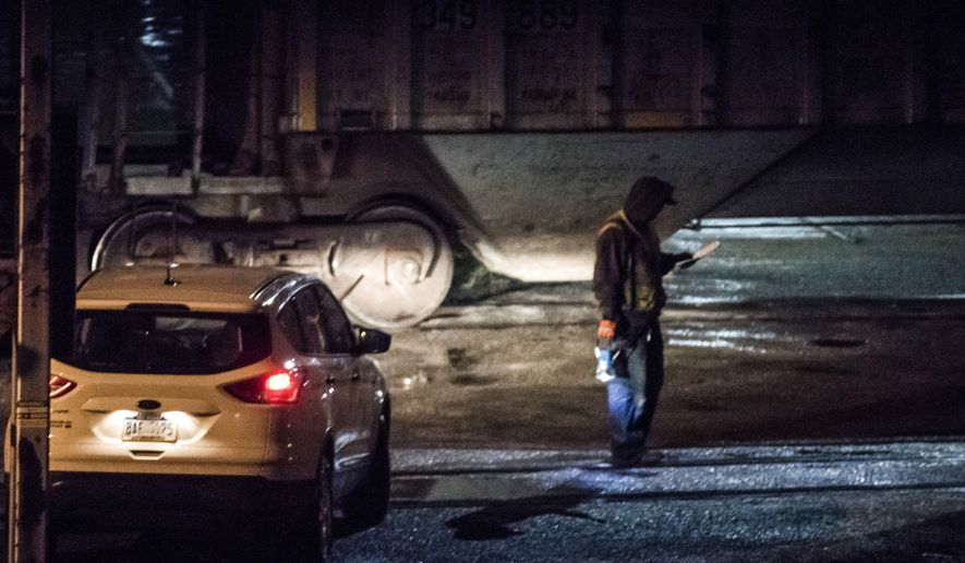 In this photo taken Monday night, April 25, 2016, workers inspect the area around a train blocking several crossings near Wadsworth Rd. in Saginaw, Mich., after police say a 20-year-old man who tried to escape police by crawling under a moving train lost both of his legs. Police say the man had two misdemeanor traffic warrants for his arrest. (Jacob Hamilton/The Saginaw News via AP) ALL LOCAL TELEVISION OUT; LOCAL TELEVISION INTERNET OUT; MANDATORY CREDIT