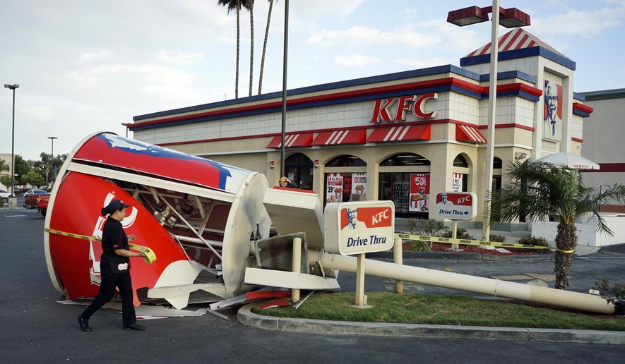 KFC employees put up caution tape around a downed sign after strong winds toppled the giant chicken bucket sign at the KFC in Long Beach, Calif., on Monday, April 25, 2016. No one was injured when the bucket came down next to the drive-thru lane. (Scott Varley/The Daily Breeze via AP) MAGS OUT; NO SALES; MANDATORY CREDIT