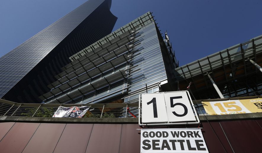 FILE - In this June 2, 2014, file photo, a sign that reads "15 Good Work Seattle" is displayed below Seattle City Hall, right, and the Columbia Center building, left, after the Seattle City Council passed a $15 minimum wage measure. As states and cities gradually implement new laws to raise wages to at least $15 an hour, they are confronting a challenge experts say has long bedeviled the nation’s municipalities: policing tens of thousands of businesses to obey wage laws. (AP Photo/Ted S. Warren, File)