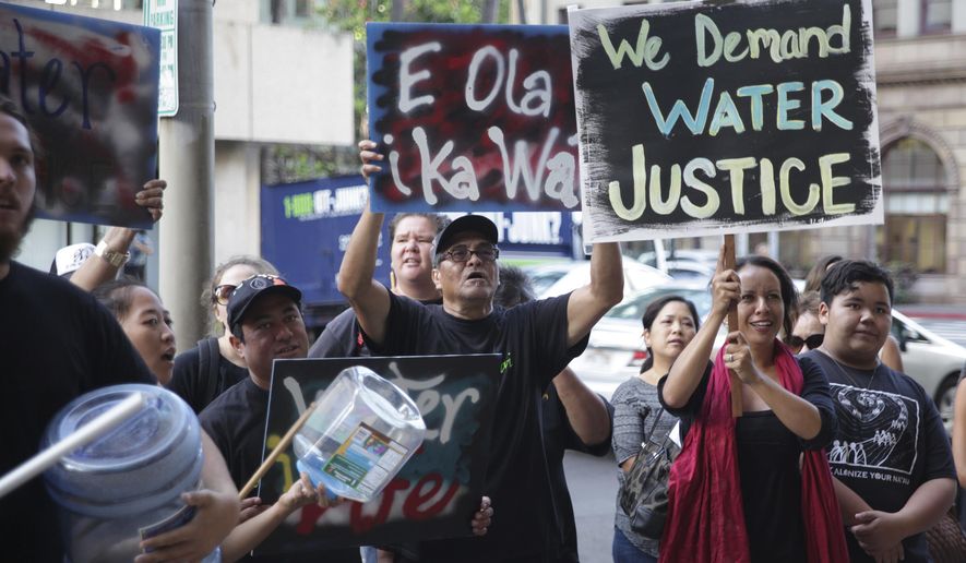 Protesters against a bill to allow companies and other water-rights holders to continue diverting water from Maui streams hold a rally outside of the Alexander & Baldwin Building in Honolulu, Tuesday, April 26, 2016. With Alexander & Baldwin scheduled to stop sugar operations at the end of the year, opponents say the company is just trying to hold onto water rights while it sucks the island dry of a public resource that many hope will be used to restore dry stream beds and farming communities. (AP Photo/Marina Riker)