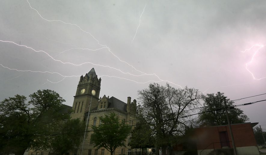Lightning illuminates the sky over the Marion County Courthouse in Marion, Kan., Tuesday, April 26, 2016. Thunderstorms bearing hail as big as grapefruit and winds approaching hurricane strength lashed portions of the Great Plains on Tuesday. (AP Photo/Orlin Wagner)