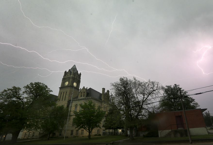 Lightning illuminates the sky over the Marion County Courthouse in Marion, Kan., Tuesday, April 26, 2016. Thunderstorms bearing hail as big as grapefruit and winds approaching hurricane strength lashed portions of the Great Plains on Tuesday. (AP Photo/Orlin Wagner)
