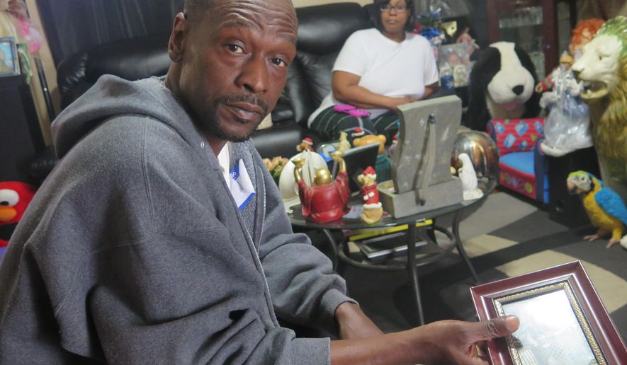 Andre Price holds a photo in his Milwaukee home Wednesday, April 27, 2016. Price's daughter Patrice Price was fatally shot in the back while driving in Milwaukee Tuesday morning. The Milwaukee County Sheriff’s Department said Patrice Price was shot by her 2-year-old son from the backseat of the car as she drove along a Milwaukee highway. The child, who was sitting in the back seat, picked up a gun that slid out from under the driver’s seat and fired it through the front seat, striking Price, the department said in a statement, citing witness accounts. Andre Price’s longtime partner, Tanya Phipps, is in the background. (AP Photo/Greg Moore)