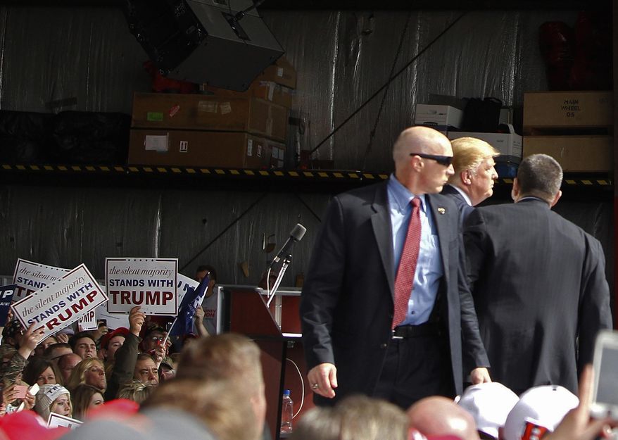 FILE - In this March 12, 2016, file photo, Secret Service agents guard Republican presidential candidate Donald Trump after a man rushed the stage during a campaign rally at the Wright Brothers Aero Hangar at Dayton International Airport in Vandalia, Ohio. Thomas DiMassimo, a 22-year-old Wright State University student, has pleaded not guilty to a misdemeanor charge of illegally entering a restricted area. During a Wednesday, April 27, 2016, status conference, participants told Magistrate Sharon Ovington that no agreement has been reached yet to avoid a trial scheduled May 31, 2016. (AP Photo/Kiichiro Sato, File)