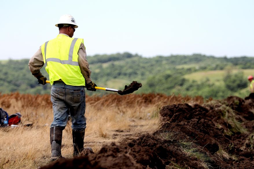 FILE - In this July 10, 2014 file photo a worker builds up a berm against a massive saltwater spill from an underground pipeline on the Fort Berthold Indian Reservation near Mandaree, N.D. Scientists say wastewater spills from oil development in western North Dakota are releasing toxins into soils and waterways. In a report published Wednesday, April 27, 2016, Duke University researchers say they detected high levels of lead, ammonium and other contaminants in surface waters affected by recent wastewater spills in the Bakken oilfield region. (AP Photo/Tyler Bell, File)