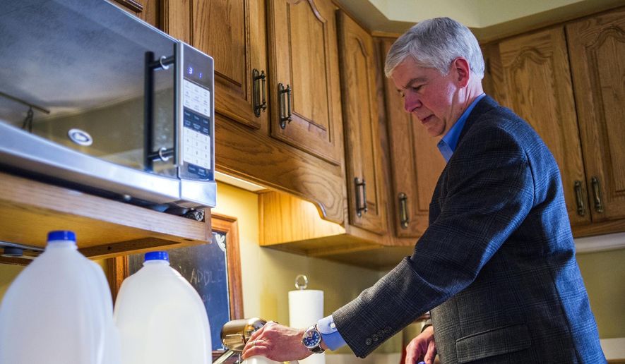 In this April 18, 2016, file photo, Michigan Gov. Rick Snyder fills jugs with filtered tap water at Cheryl Hill&#x27;s house, in Flint, Mich. (Jake May/The Flint Journal-MLive.com via AP File) 