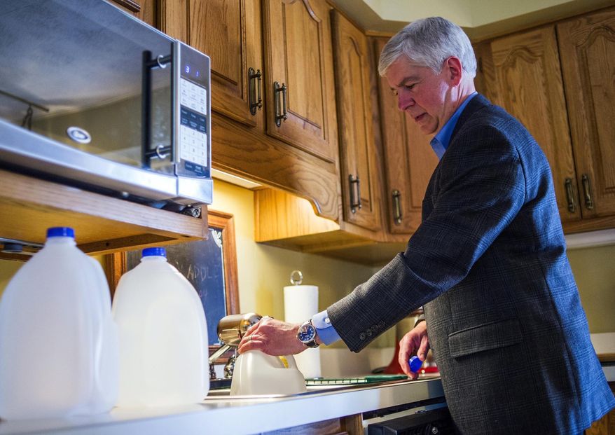 In this April 18, 2016, file photo, Michigan Gov. Rick Snyder fills jugs with filtered tap water at Cheryl Hill&#x27;s house, in Flint, Mich. (Jake May/The Flint Journal-MLive.com via AP File) 