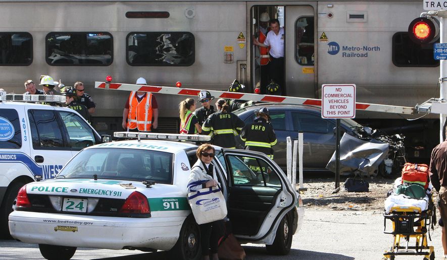 Firefighters and police officers work a collision site of a northbound Metro-North train and a vehicle in Bedford Hills, N.Y., Wednesday, April 27, 2016. Officials said the car apparently became stuck on the tracks and the driver got out before the train clipped the vehicle. (Frank Becerra Jr./The Journal News via AP) MANDATORY CREDIT