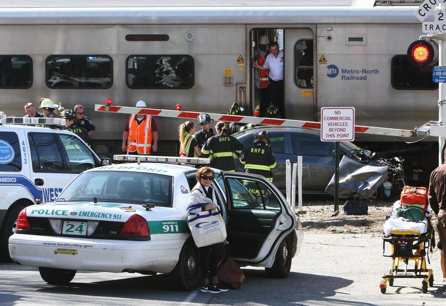 Firefighters and police officers work a collision site of a northbound Metro-North train and a vehicle in Bedford Hills, N.Y., Wednesday, April 27, 2016. Officials said the car apparently became stuck on the tracks and the driver got out before the train clipped the vehicle. (Frank Becerra Jr./The Journal News via AP) MANDATORY CREDIT
