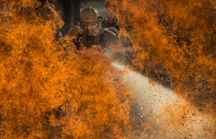 Hon. mention in the Pictorial category: Three military students assigned to the 312th Training Squadron battle a fire during a liquid fire scenario at the Louis F. Garland Department of Defense Fire Academy, Oct. 19, 2015. During liquid fire training, the students rotate through three-man iterations of low and high fires while moving through water. The joint DOD school is comprised of Air Force, Army, Navy, Marine and civil service students. IMAGE: STAFF SGT. VERNON YOUNG JR., USAF