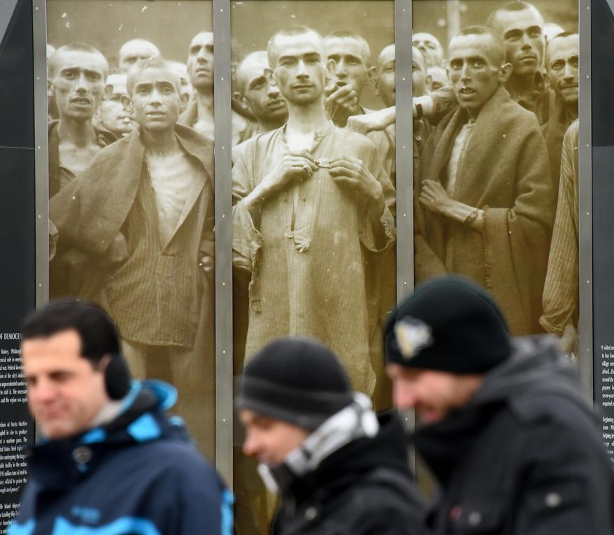 ADVANCE FOR WEEKEND EDITIONS - In this Jan. 27, 2016 photo, people walk past images of concentration camp survivors at the Southwestern Pennsylvania World War II Memorial in Pittsburgh. (Bob Donaldson/Pittsburgh Post-Gazette via AP) MANDATORY CREDIT