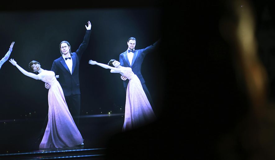 Mizuho Shinden watches the hologram of dancers with her face attached, far left, featuring actors Brad Pitt, second left, Leonardo DiCaprio, far right, at the newly opened Hologram Dance Theater at Madame Tussauds in Tokyo, Thursday, April 28, 2016. Madam Tussauds in Tokyo is launching an event allowing visitors to virtually join a 3D world where they can dance with holograms of celebrities such as Brad Pitt, Leonardo DiCaprio, and Lady Gaga. (AP Photo/Eugene Hoshiko)