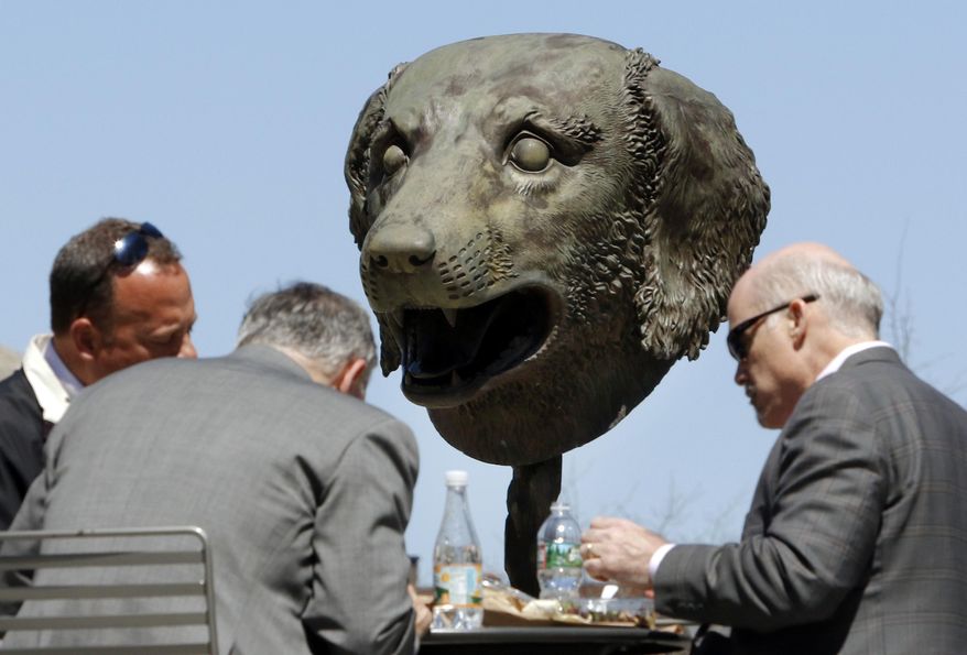 In this Wednesday, April 27, 2016 photo, one of 12 gigantic bronze animal heads representing the signs of the Zodiac by Chinese artist Ai Weiwei stands behind businessmen eating lunch on the Rose Kennedy Greenway in Boston. The sculptures are scheduled to remain on public display in the park through October. (AP Photo/Bill Sikes)