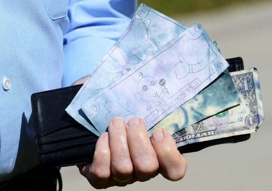 ADVANCE FOR MONDAY, MAY 2, 2016- In this March 24, 2016 photo, Laurance Davis holds the wallet containing drawings, a note and a dollar bill, that was found at the scene of his August 2015 mugging, on Lady's Island, S.C. (Jay Karr /The Island Packet via AP) MANDATORY CREDIT