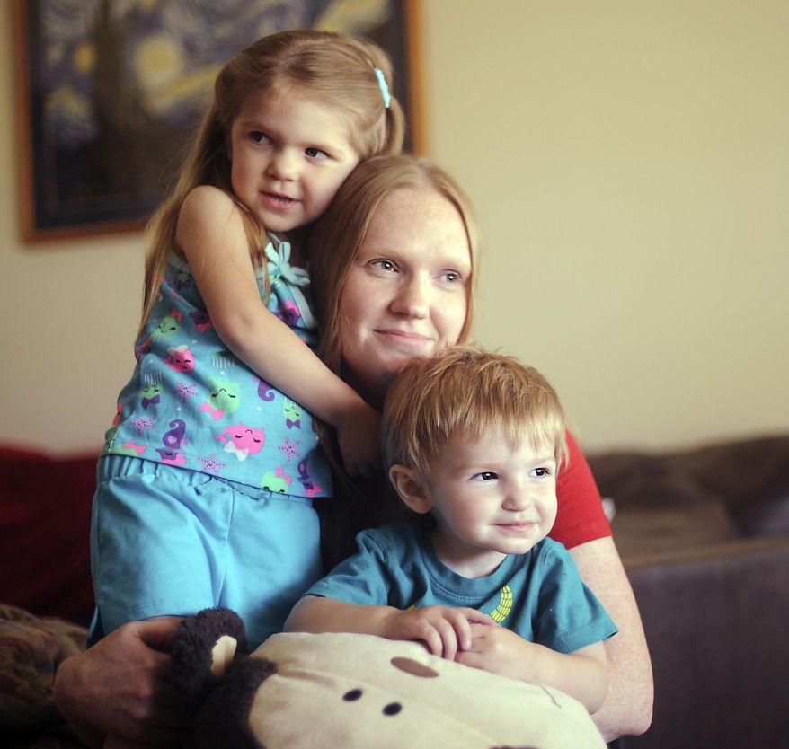 Jennifer Adair holds her two children, Lily, left, and Josh, at their home in Athens, Ala. Tuesday, April 26, 2016. In Limestone County April 27, 2011, four people died in the storms, among the 234 killed statewide. Adair is one of the survivors. She recalls pieces of her home in Limestone County whipping across her back as an EF5 tornado roared above her. She said she felt the pull of the winds as she screamed for protection. (Jeronimo Nisa/The Decatur Daily via AP)