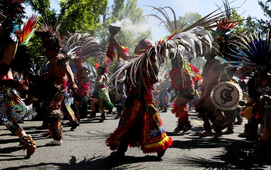 Traditional Aztec dancers headed up the annual El Comite May Day March for Worker and Immigrant Rights, stopping to perform numerous times, Sunday May 1, 2016, in Seattle. (Ken Lambert/The Seattle Times via AP)