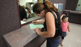 A woman fills out a form at the Sacramento County welfare office in California. (Associated Press/File)
