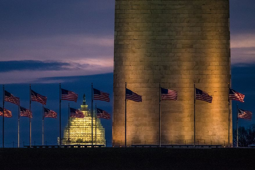 In this Dec. 31, 2015, file photo, flags around the Washington Monument fly in the gentle breeze at daybreak on a warmer than average day in Washington. The U.S. Capitol is in the background. (AP Photo/J. David Ake, File)