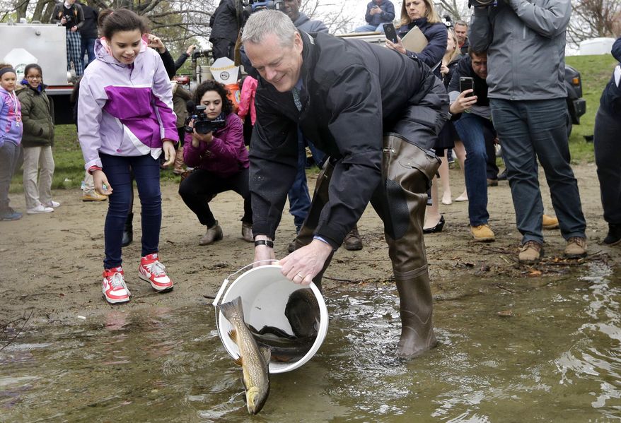 Massachusetts Gov. Charlie Baker tosses trout into Jamaica Pond, Wednesday, May 4, 2016, in Boston as he participates in the annual spring fish stocking event. (AP Photo/Elise Amendola)