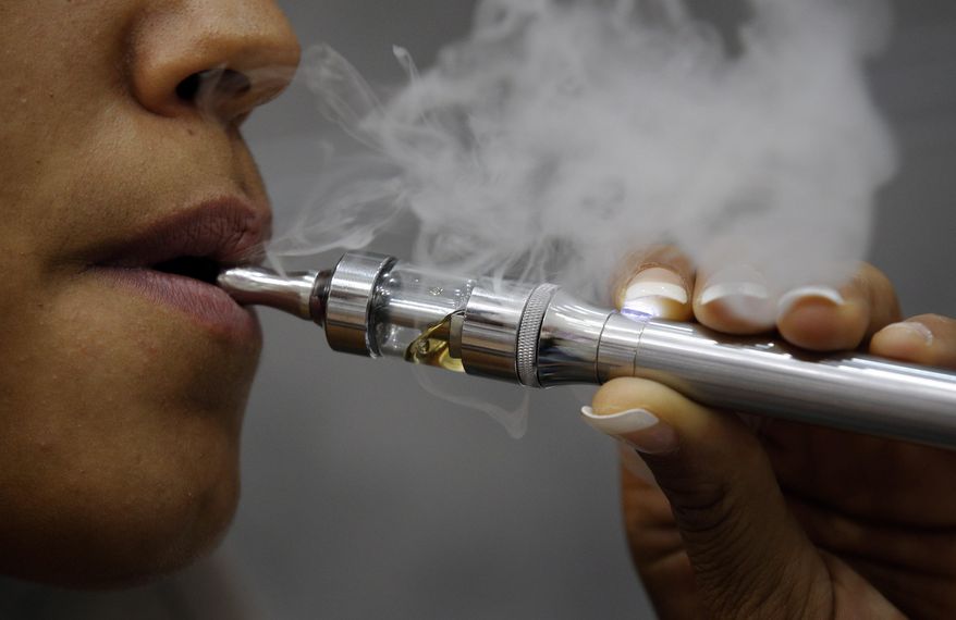 FILE- In this Oct. 8, 2013 file photo, Kathleene, an electronic cigarette store employee, smokes an electronic cigarette in Paris. The European Union’s top court has approved on Wednesday May 4, 2016 new rules requiring plain cigarette packs, banning menthol cigarettes and regulating the growing electronic cigarette market.(AP Photo/Christophe Ena, File)