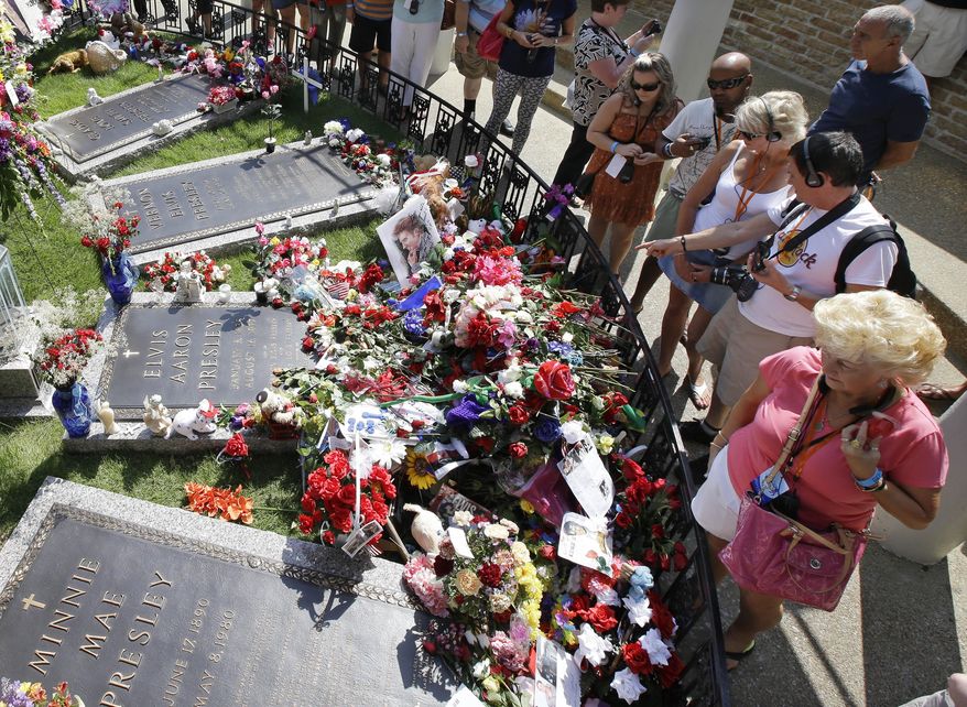 FILE - In this Aug. 16, 2012, file photo, Elvis Presley fans visit his grave at Graceland, Presley's Memphis, Tenn., home. The operators of Graceland said the tourist attraction centered on the life and music of Elvis Presley has received its 20 millionth paid visitor Monday, May 2, 2016. (AP Photo/Mark Humphrey, File)