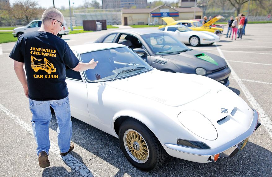 ADVANCE FOR WEEKEND EDITIONS - In this Saturday, April 23, 2016 photo, Pat Brosnan gestures toward his 1973 Opel GT in the parking lot of Traxler Park after a meeting of the Janesville Cruisers Car Club in Janesville, Wis. The club is working to organize and seek approval from the City of Janesville to hold a cruise night in June, an activity that's been banned in downtown Janesville since the early 1990s. (Anthony Wahl/The Janesville Gazette via AP) MANDATORY CREDIT