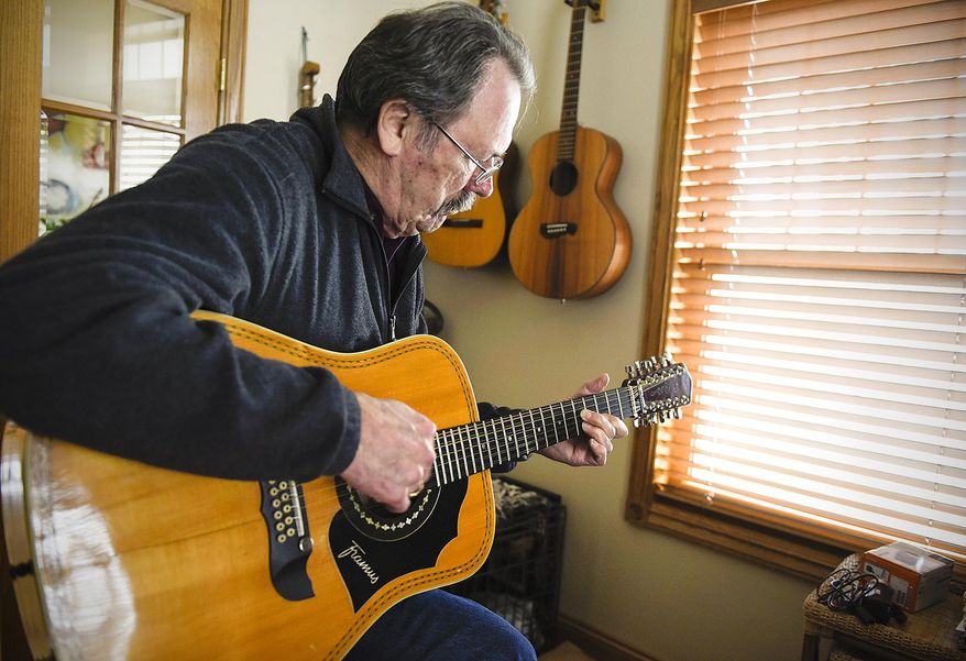 ADVANCE FOR WEEKEND EDITIONS MAY 7-8 - In this April 5, 2016 photo, Al Hams, 72, plays one of his guitars at his home in Sauk Rapids. Minn. Al Hams is 72. He has Parkinson's disease, very likely due to his exposure to the chemical defoliant Agent Orange during the year he served with the U.S. Army in Vietnam. He calls that the "missing year" a period Hams tried to forget. (Jason Wachter/St. Cloud Times via AP) NO SALES; MANDATORY CREDIT