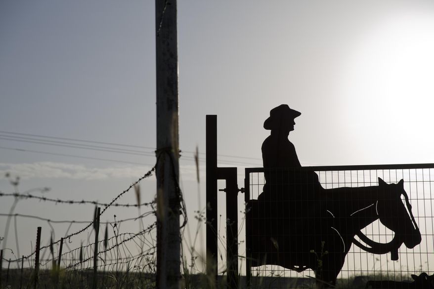 In this Monday, April 11, 2016 photo shows, a cowboy shaped metal gate of a ranch in the Israeli controlled Golan Heights near the border with Syria. The small brotherhood of about 100 cowboys who are responsible for raising the primary source of Israeli domestic beef know well they face a particular set of unique challenges. For starters, they operate on a relatively small patch of land made up mostly nature reserves and military grounds so everything they do has to be coordinated with authorities. Israel captured Golan from Syria in the 1967 war. (AP Photo/Ariel Schalit)