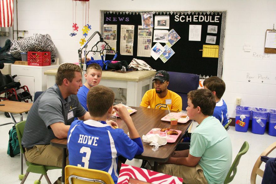 In this April 21, 2016 photo, Nate Sparks, left, and Rubyn Branch, facing, who are juniors at Centre College and on the football team, talk to students at the Anchored Men's Club in Danville, Ky. The Anchored Men’s Club has been meeting for close to two months now in the classroom of Robin Moler, special education teacher at Bate Middle School. Branch and Sparks said they thought everything the club was about was just “awesome.” “We had a mutual feeling that we wished we’d had an experience like this in middle school,” said Sparks. (Kendra Peek/The Advocate-Messenger via AP) TABLOIDS OUT; MANDATORY CREDIT