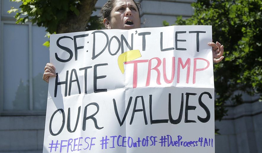 Teresa Molina holds up a sign at a rally outside of City Hall in San Francisco, Tuesday, May 10, 2016. Officials in famously progressive San Francisco have long sanctioned protections for people in the country illegally, going so far as to prohibit city workers from asking about a person's immigration status. (AP Photo/Jeff Chiu)