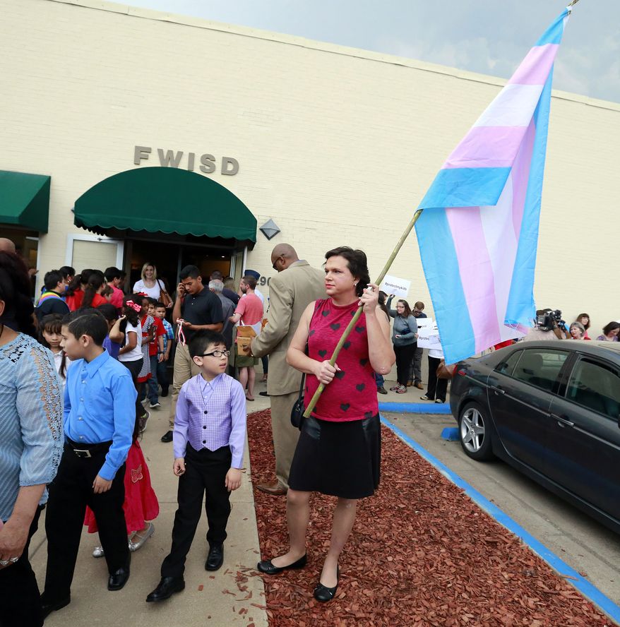 In this photo taken Tuesday, May 10, 2016, a young boy leaving a special recognition ceremony at the Fort Worth School board meeting looks at Karli Rampage, right, of Irving, Texas, who came in support of her transgender community at the Fort Worth ISD Board of Education complex, in Fort Worth, Texas. Fort Worth Superintendent Kent Scribner announced rules last month allowing transgender students access to single-stall restrooms. (Tom Fox/The Dallas Morning News via AP) **FILE**