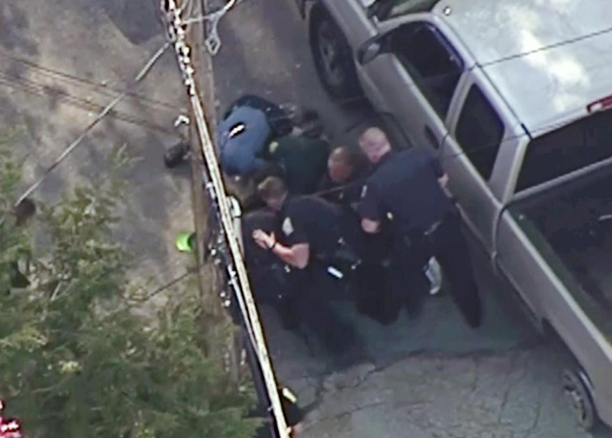 This aerial image made from a helicopter video provided by WHDH shows several officers pummeling Richard Simone, who had exited his vehicle and kneeled on the ground after a high-speed police pursuit, in Nashua, N.H., Wednesday, May 11, 2016. The chase went through several towns before ending in Nashua. (Courtesy WHDH via AP) MANDATORY CREDIT; BOSTON OUT