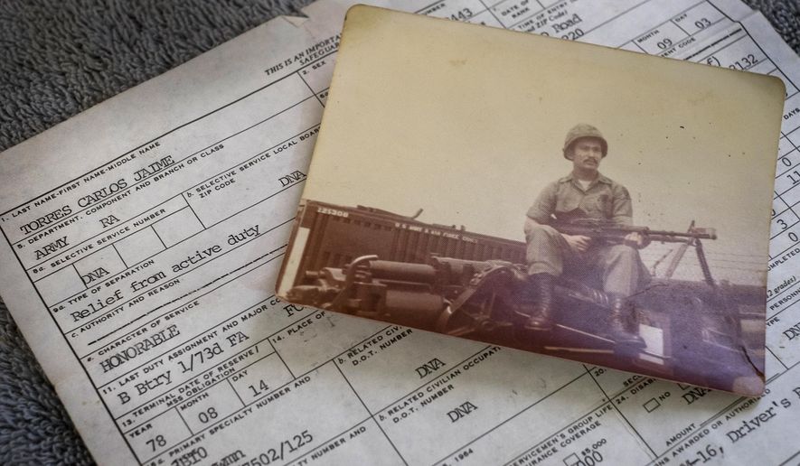ADVANCE FOR USE SUNDAY, MAY 15 - In this photo taken Feb. 23, 2016, a photograph of Amry veteran Carlos Torres holding a machine gun during his military service is displayed in Reynosa, Mexico, along with his honorable discharge paperwork. Forty-four years after he volunteered for the U.S. Army during the Vietnam War, Torres is among an untold number of U.S. military veterans who’ve been deported to Mexico over the past decade after arrests or prison sentences. (Rodolfo Gonzalez/Austin American-Statesman via AP)