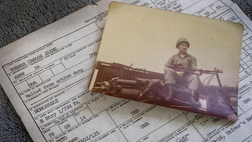 ADVANCE FOR USE SUNDAY, MAY 15 - In this photo taken Feb. 23, 2016, a photograph of Amry veteran Carlos Torres holding a machine gun during his military service is displayed in Reynosa, Mexico, along with his honorable discharge paperwork. Forty-four years after he volunteered for the U.S. Army during the Vietnam War, Torres is among an untold number of U.S. military veterans who’ve been deported to Mexico over the past decade after arrests or prison sentences. (Rodolfo Gonzalez/Austin American-Statesman via AP)