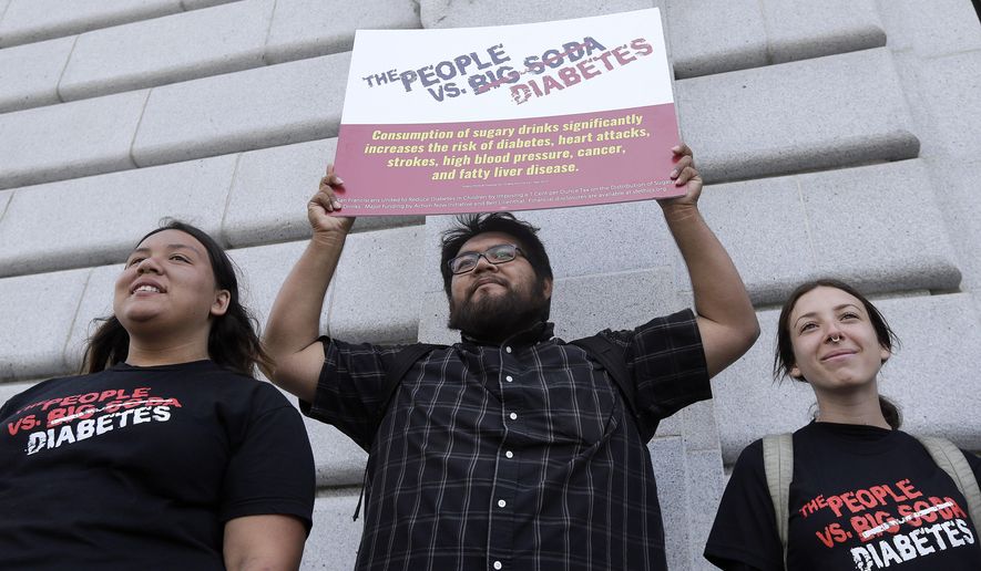 Jesus Alonso, center, holds up a sign between other volunteers after a news conference announcing that San Francisco backers of a tax on sugary beverages have enough signatures to put the measure on the November ballot outside of City Hall in San Francisco, Thursday, May 12, 2016. This would be San Francisco's second attempt in two years trying to put a tax on the highly caloric drinks that some public health advocates say contributes to obesity. A 2014 attempt failed to garner the two-thirds approval needed for a dedicated tax. (AP Photo/Jeff Chiu)