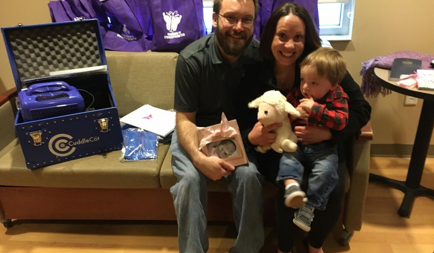 ADVANCE FOR WEEKEND EDITIONS - In this April 22, 2016 photo, Emma's Footprints, a Valparaiso-based foundation that provides support to families dealing with premature birth and infant loss, recently donated a Cuddle Cot to Porter Regional Hospital. The device preserves the bodies of late infants so their families can have more time with them. The charity was started by Joseph and Amelia Kowalisyn after the death of their daughter, Emma, at 23 days old. The couple are pictured with their son, Alex. (Giles Bruce/The Times via AP) MANDATORY CREDIT
