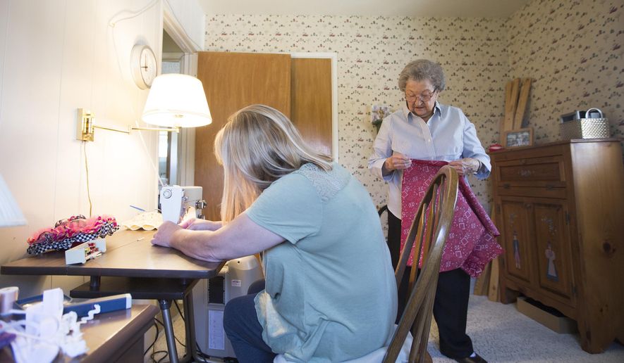 In this photo taken Wednesday, May 4, 2016, Kris Evertsen, of Clinton, left, threads the needle of her mom's sewing machine at her mom's house in Washington Terrace, Utah. Since Helen Peterson, 94, started making dresses to donate to girls in Africa in January she has made over 80 dresses. Kris, Helen's youngest daughter, spends most days with her and helps with things such as preparing food and running errands. (Briana Scroggins/Standard-Examiner via AP)