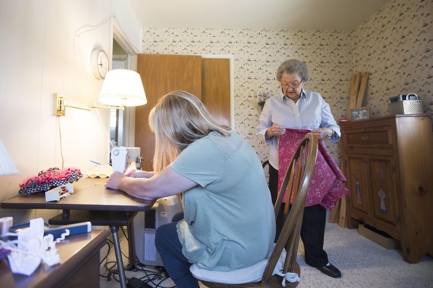 In this photo taken Wednesday, May 4, 2016, Kris Evertsen, of Clinton, left, threads the needle of her mom's sewing machine at her mom's house in Washington Terrace, Utah. Since Helen Peterson, 94, started making dresses to donate to girls in Africa in January she has made over 80 dresses. Kris, Helen's youngest daughter, spends most days with her and helps with things such as preparing food and running errands. (Briana Scroggins/Standard-Examiner via AP)