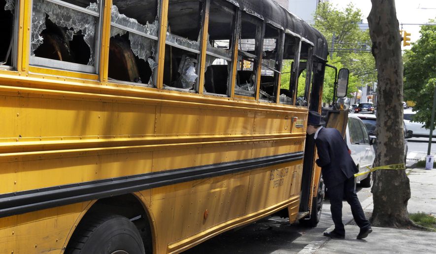 An Orthodox Jewish boy peeks into the school bus that was burned Sunday May 8, 2016, in the Crown Heights section of the Brooklyn borough of New York, Wednesday May 11, 2016. When a group of young, black children set fire to a school bus outside a Jewish school this week, it evoked bad memories of a violent riot in the same Brooklyn neighborhood 25 years ago. Relations between blacks and Jews in Crown Heights have been peaceful for many years, but some community leaders say tensions remain. (AP Photo/Richard Drew)
