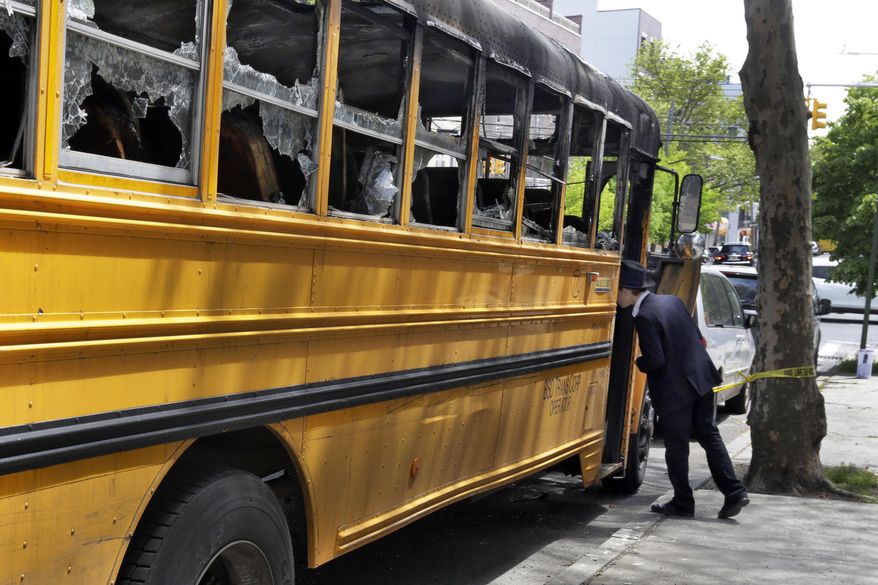 An Orthodox Jewish boy peeks into the school bus that was burned Sunday May 8, 2016, in the Crown Heights section of the Brooklyn borough of New York, Wednesday May 11, 2016. When a group of young, black children set fire to a school bus outside a Jewish school this week, it evoked bad memories of a violent riot in the same Brooklyn neighborhood 25 years ago. Relations between blacks and Jews in Crown Heights have been peaceful for many years, but some community leaders say tensions remain. (AP Photo/Richard Drew)