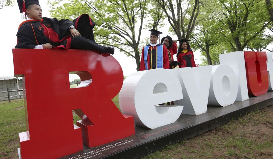 Rutgers University senior Christopher Mazareno strikes a pose for a photograph while some fellow seniors wait their turn, as they try to get some photographic memories out of the way before the crowds show up for Sunday's graduation ceremonies Friday, May 13, 2016 in Piscataway, N.J. President Obama will speak at Rutgers University's commencement, Sunday. (AP Photo/Mel Evans)