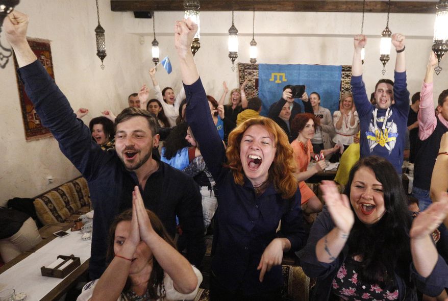 People celebrate while watching TV as Jamala of Ukraine wins the final of the Eurovision Song Contest in Stockholm, in a restaurant in Kiev, Ukraine, Sunday, May 15, 2016. Susana Jamaladinova, using the stage name Jamala, has won the 2016 Eurovision Song Contest and received the highest score for her song "1944," a melancholic tune about the 1944 deportation of Crimean Tatars by Soviet authorities. in a vote from juries and TV viewers across Europe after the 26 finalists performed at Stockholm's Globe arena. (AP Photo/Sergei Chuzavkov)