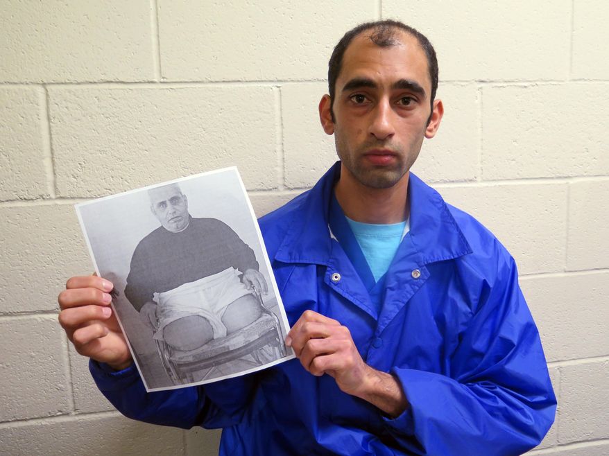 In this Thursday, Dec. 10, 2015 photo, Mounis Hammouda sits in an immigration detention center in Eloy, Ariz., showing a picture of his father, Jameel Hammouda, who he says was tortured by Hamas because he worked for a rival organization. Mounis Hammouda says he fled Gaza because his family was targeted by Hamas, the Islamic political party. His father still lives in Gaza. (AP Photo/Astrid Galvan)