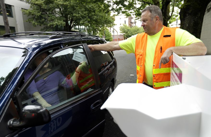 Election worker Randy Polivka helps a motorist drop off her ballot at a ballot drop box site in Portland, Ore., Monday, May 16, 2016. Oregon elections are vote-by-mail where voters can also drop their ballots off days before the election. Oregon's primary is May 17. (AP Photo/Don Ryan)