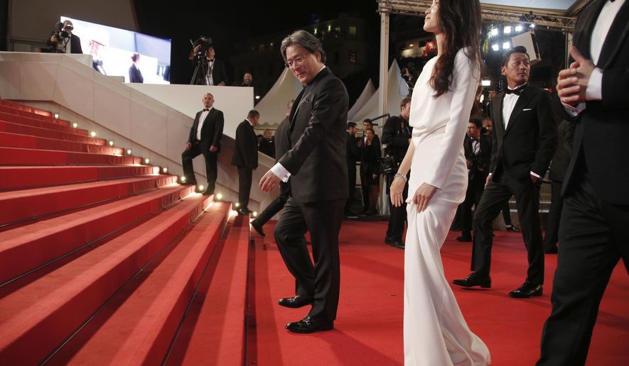 Director Park Chan-Wook, centre and actress Kim Tae-Ri pose for photographers upon arrival at the screening of the film The Handmaiden at the 69th international film festival, Cannes, southern France, Saturday, May 14, 2016. (AP Photo/Thibault Camus)