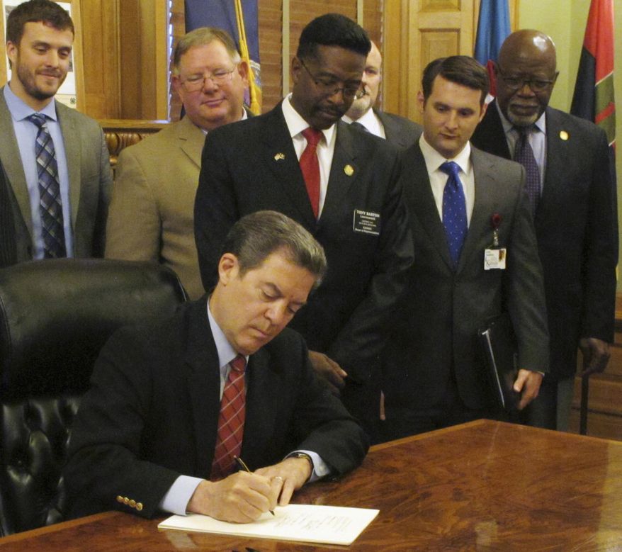 Kansas Gov. Sam Brownback signs legislation tightening the state's lifetime limits on cash assistance and making other changes in welfare policies, Monday, May 16, 2016, at the Statehouse in Topeka, Kan. Brownback says such changes help move people out of poverty and government dependence and into the work force. (AP Photo/John Hanna)