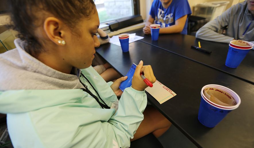 In this May 5, 2016 photo, student Chloe Colston, 15, labels a cup for mosquito larva collection at her school in Mahanttan, KS. The mosquitoes that can spread the disease Zika are already buzzing in places around the United States but the U.S. government could use a little help figuring out exactly where. The U.S. Department of Agriculture says high school students can do this important work using plastic cups and brown paper towels, mapping hotspots for mosquito controllers. (AP Photo/Josh Replogle)