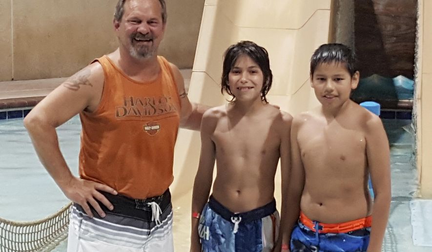 This Monday, May 16, 2016, photo provided by the Rapid City Police Department shows Rick Volk, left, of Phoenix, posing with Wisdom Bass-Robinson, center, and Btin Spears, both from Walthill, Neb., after the three helped save the life of a young girl who nearly drowned at a hotel swimming pool in Rapid City, S.D. The boys noticed the girl face-down in the pool and pulled her from the water. Volk, with the help of other bystanders began CPR and revived the girl, who was taken to a hospital and is expected to be fine. (Sgt. Darren Soucy/Rapid City Police Department via AP)