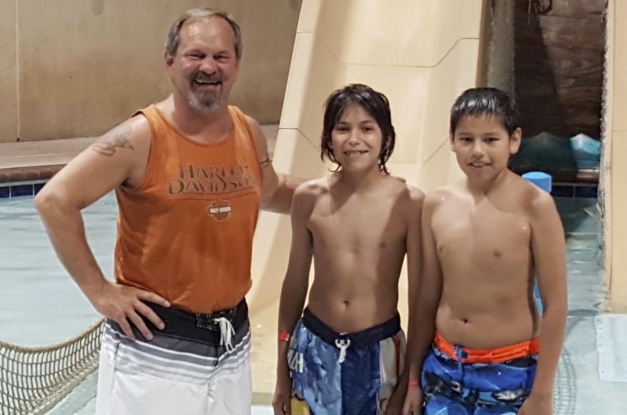 This Monday, May 16, 2016, photo provided by the Rapid City Police Department shows Rick Volk, left, of Phoenix, posing with Wisdom Bass-Robinson, center, and Btin Spears, both from Walthill, Neb., after the three helped save the life of a young girl who nearly drowned at a hotel swimming pool in Rapid City, S.D. The boys noticed the girl face-down in the pool and pulled her from the water. Volk, with the help of other bystanders began CPR and revived the girl, who was taken to a hospital and is expected to be fine. (Sgt. Darren Soucy/Rapid City Police Department via AP)